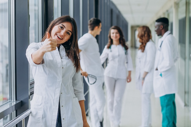 Foto gratuita joven doctora con pulgares arriba gesto, de pie en el pasillo del hospital