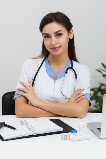 Joven doctora sentado con las manos cruzadas