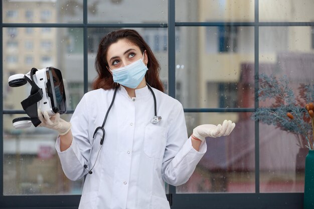 Joven doctora sosteniendo gafas VR y pensando