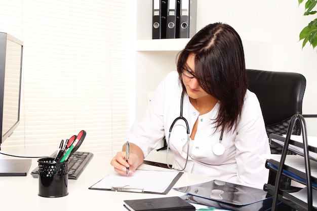 Foto gratuita joven doctora en su consultorio