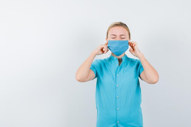 Foto gratuita joven doctora tapando los oídos con los dedos en uniforme y mirando molesto aislado