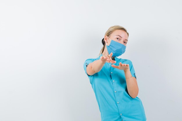 Foto gratuita joven doctora en uniforme apuntando y mirando alegre