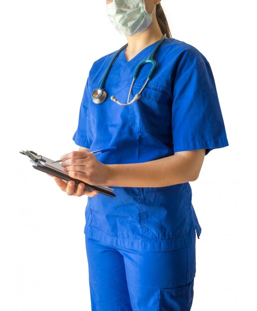 Joven doctora en un uniforme médico azul y una máscara tomando notas en un cuaderno