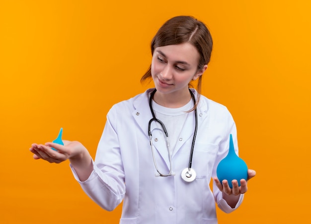 Joven doctora vistiendo bata médica y estetoscopio en pared verde aislada