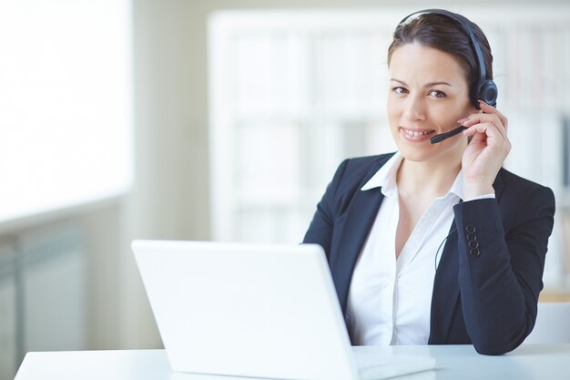 Joven ejecutiva trabajando con auriculares y portátil