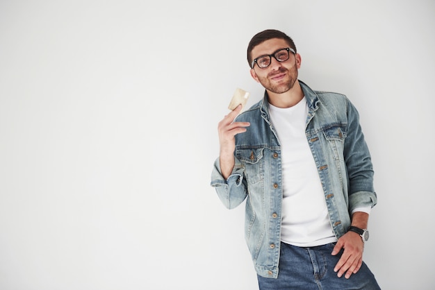 Joven ejecutivo de negocios masculino guapo en vestimenta casual con una tarjeta de crédito en los bolsillos en blanco