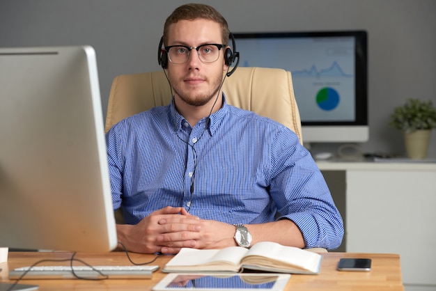 Joven ejecutivo de negocios usando auriculares mirando a la cámara