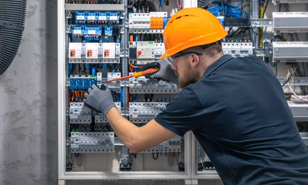 Joven electricista adulto ingeniero civil atornillando equipos en la caja de fusibles