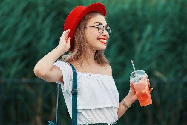 Una joven elegante con una bebida refrescante mientras camina