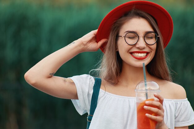 Una joven elegante con una bebida refrescante mientras camina