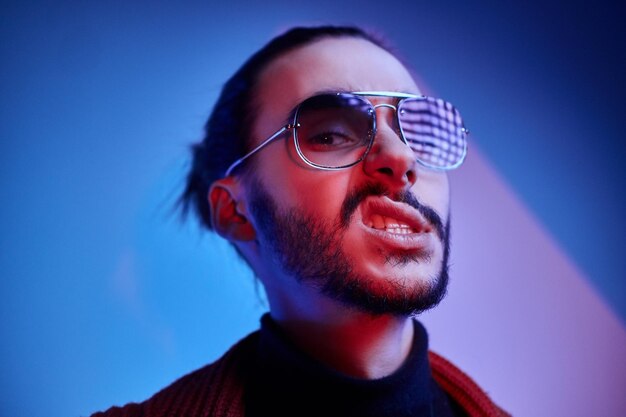 Un joven elegante con gafas de sol muestra una emoción agresiva mientras muestra sus dientes.