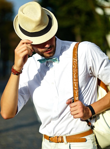 Foto gratuita joven elegante sexy modelo guapo hombre turista en ropa casual estilo de vida en la calle con sombrero con bolsa