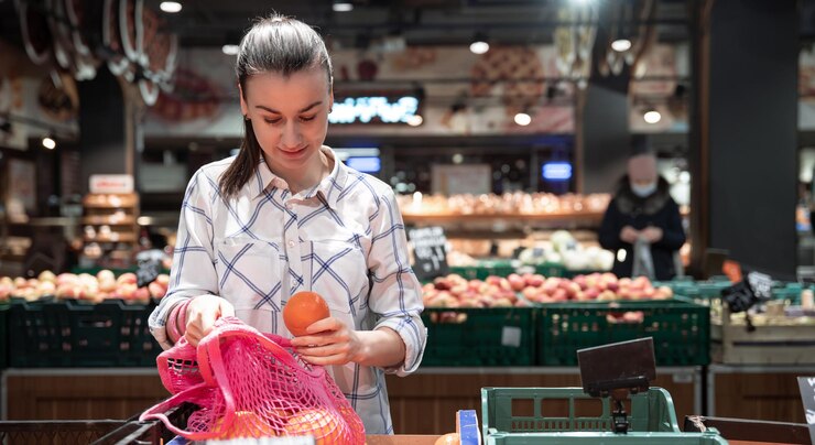 Foto gratuito una joven elige frutas en un supermercado.