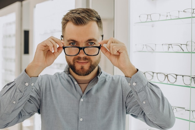 Joven eligiendo gafas en la tienda de óptica