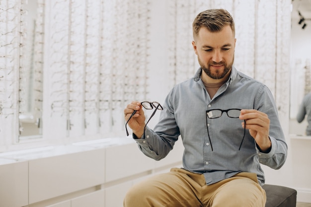 Joven eligiendo gafas en la tienda de óptica