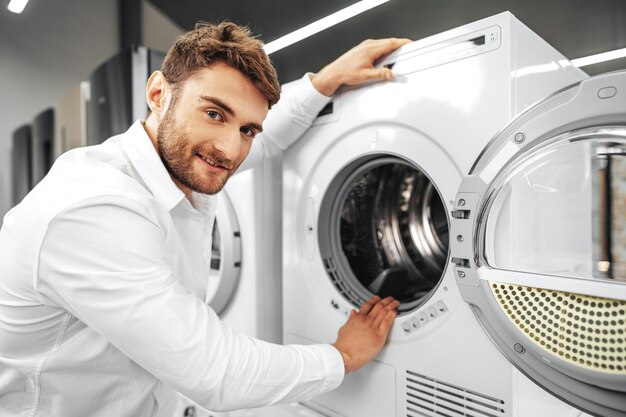 Joven eligiendo nueva lavadora en la tienda de electrodomésticos