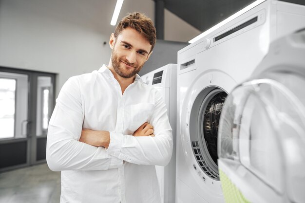 Joven eligiendo nueva lavadora en la tienda de electrodomésticos