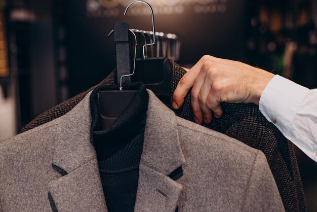 Joven eligiendo paños en la tienda de ropa masculina