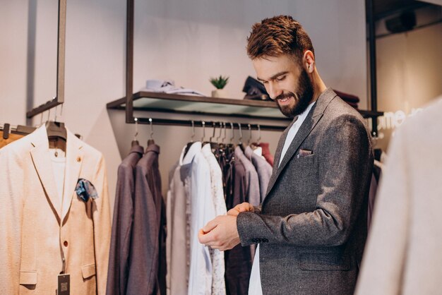 Joven eligiendo paños en la tienda de ropa masculina