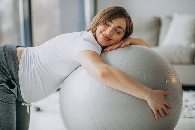 Joven embarazada ejercicio de yoga con fit ball en casa