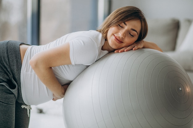 Joven embarazada ejercicio de yoga con fit ball en casa