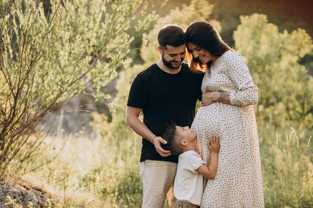 Joven embarazada con marido e hijo en un bosque