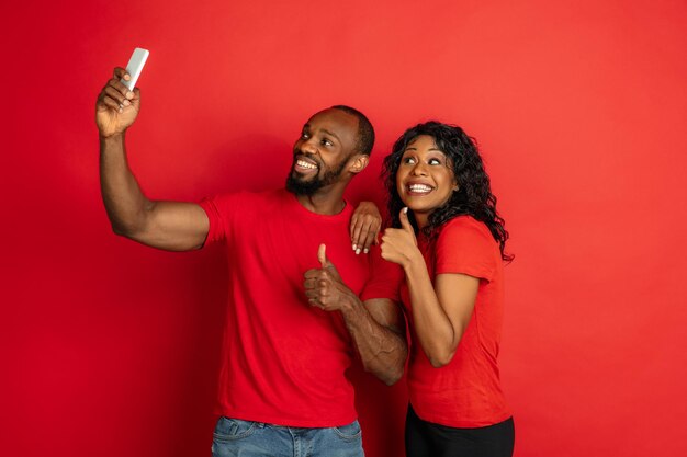 Joven emocional afroamericano y mujer en rojo