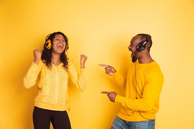 Joven emocional afroamericano y mujer sobre fondo amarillo