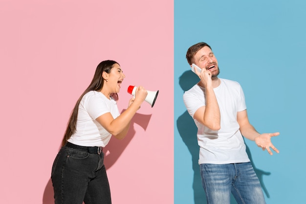 Joven emocional y mujer en pared rosa y azul