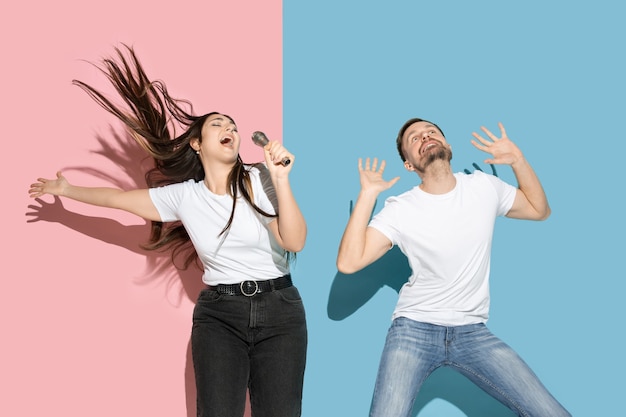 Foto gratuita joven emocional y mujer en pared rosa y azul