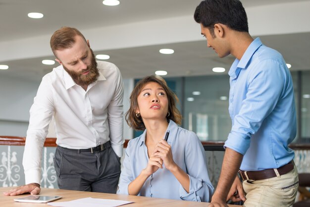 Joven empleado pidiendo ayuda a sus colegas.