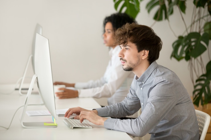 Foto gratuito joven empleado serio centrado en el trabajo informático en una oficina multirracial