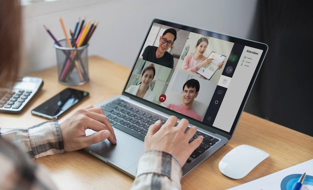 Joven empresaria asiática trabajando de forma remota desde casa y reunión de videoconferencia virtual con colegas empresarios. distanciamiento social en el concepto de oficina en casa.