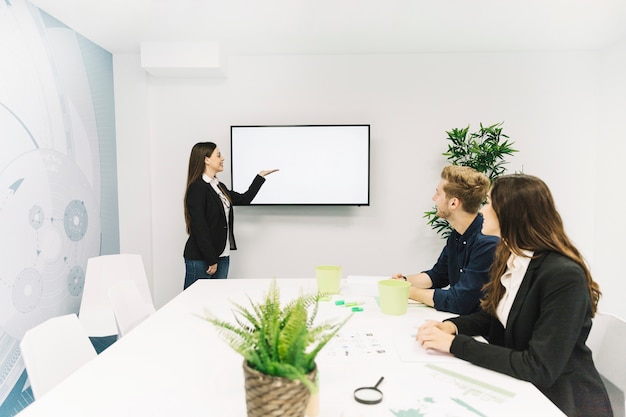 Joven empresaria dando presentación a sus colegas en reunión de negocios