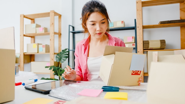 Foto gratuita joven empresaria empresaria de asia comprueba la orden de compra del producto en stock y ahorra en el trabajo de la tableta en la oficina en casa propietario de una pequeña empresa, entrega de mercado en línea, concepto independiente de estilo de vida.