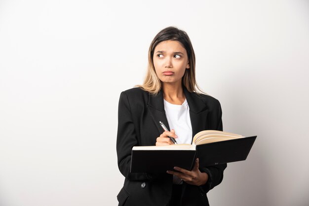 Joven empresaria escribiendo en portapapeles con lápiz.