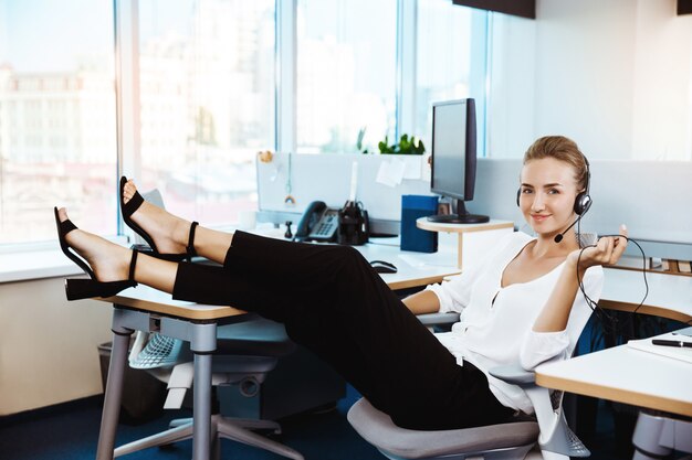 Joven empresaria exitosa hermosa descansando, relajándose en el lugar de trabajo, oficina