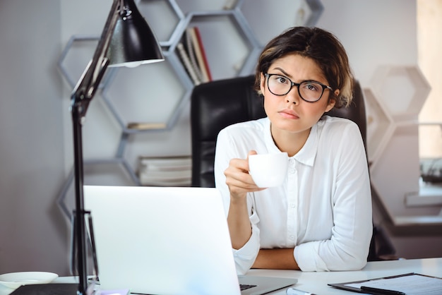 Joven empresaria hermosa confía en beber café en el lugar de trabajo en la oficina.