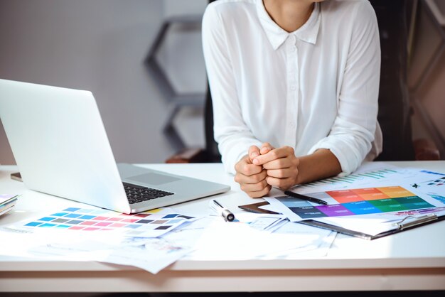 Joven empresaria hermosa sentada en el lugar de trabajo en la oficina. De cerca.