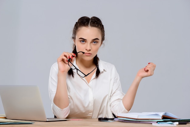 Joven empresaria hermosa sentada en el lugar de trabajo sobre la pared púrpura