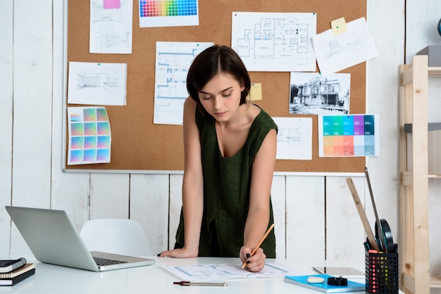 Joven empresaria hermosa trabajando con dibujos en el lugar de trabajo