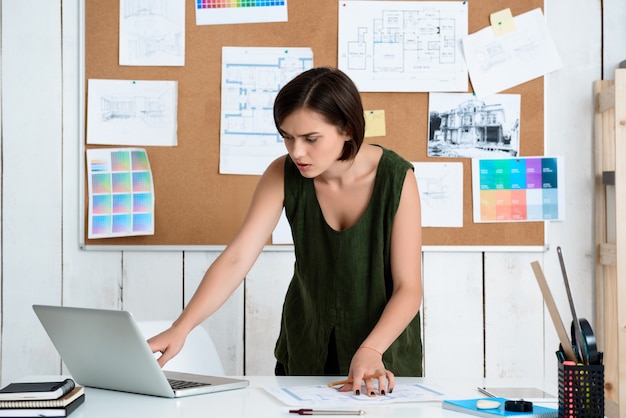 Joven empresaria hermosa trabajando con dibujos en el lugar de trabajo