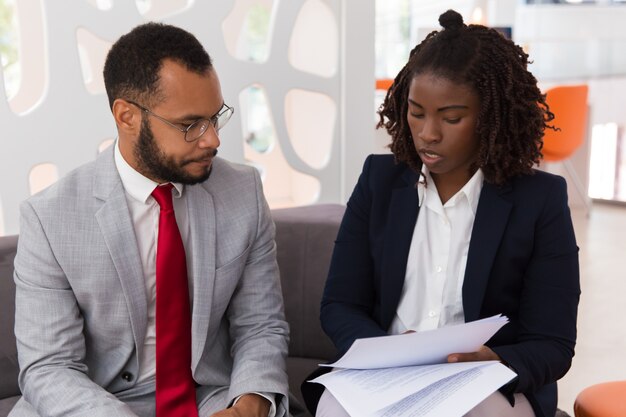 Joven empresaria mostrando contrato a colega masculino