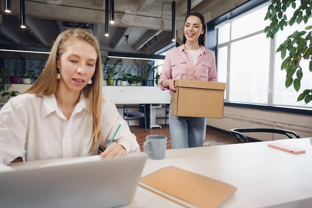 Foto gratuita joven empresaria sosteniendo una caja de pertenencias personales a punto de dejar la oficina después de dejar el trabajo