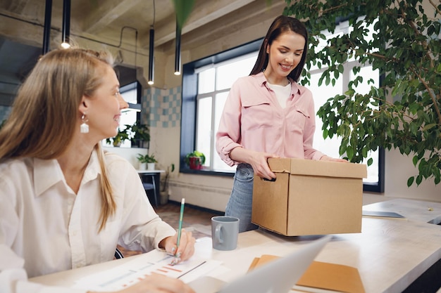 Joven empresaria sosteniendo una caja de pertenencias personales a punto de dejar la oficina después de dejar el trabajo