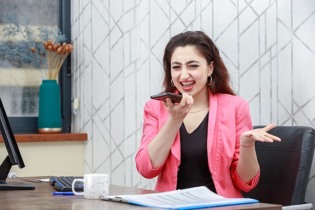 Joven empresaria sosteniendo su teléfono y riendo Foto de alta calidad