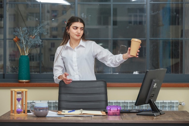 Joven empresaria sosteniendo una taza de café y mirándola