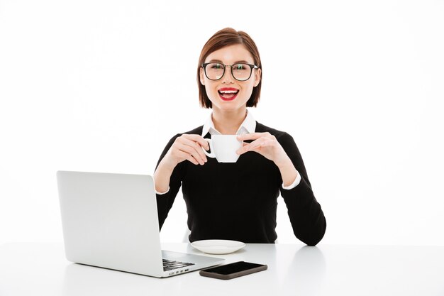 Joven empresaria con taza de café o té y computadora portátil