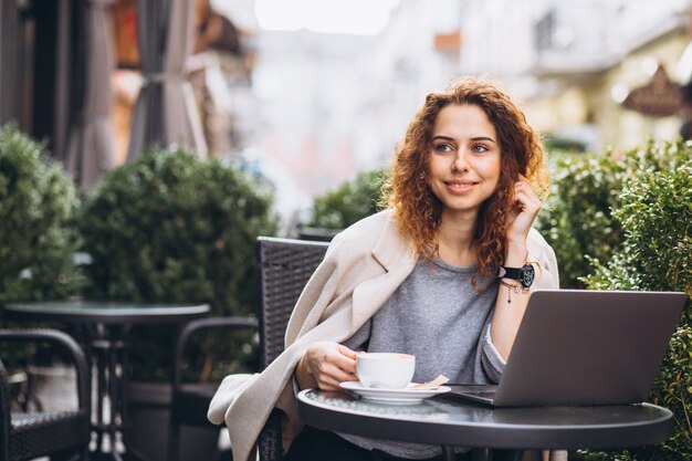 Joven empresaria trabajando en una computadora fuera del café