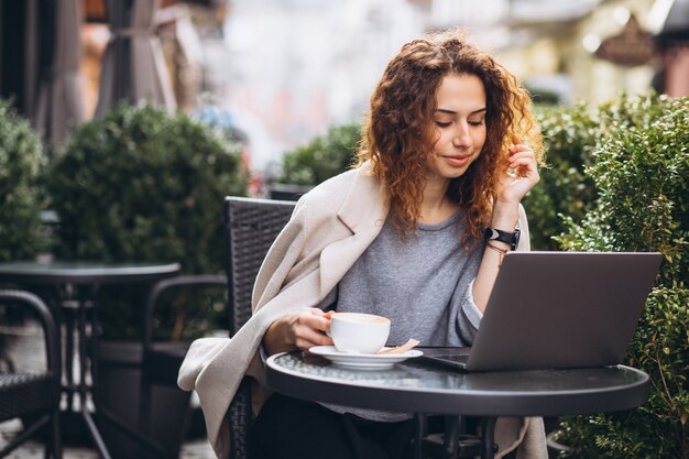 Joven empresaria trabajando en una computadora fuera del café